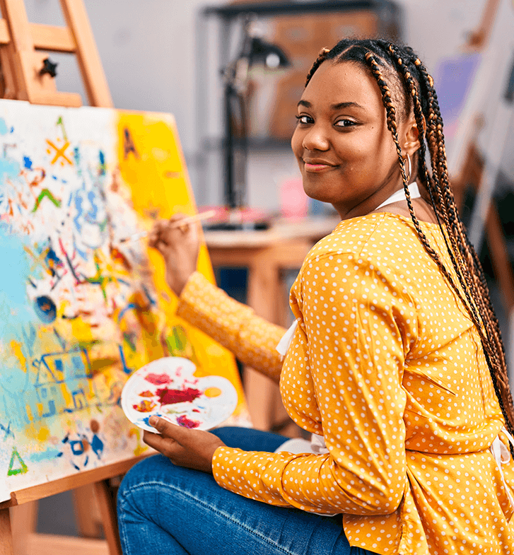 Menina negra pintando uma tela com várias cores